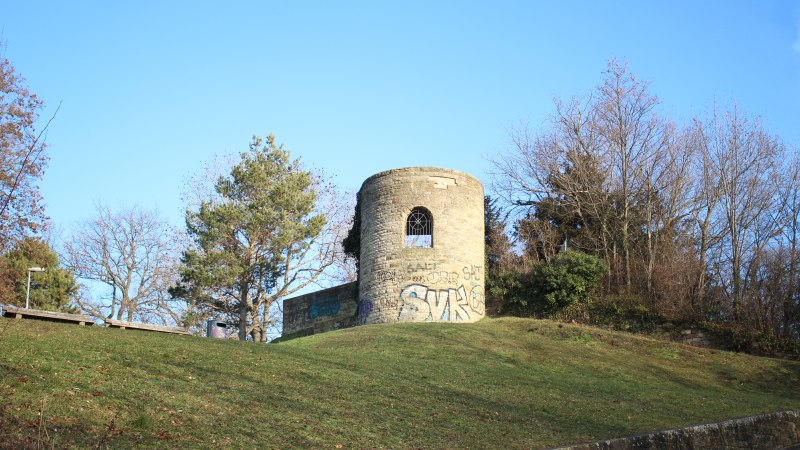 Eine alte, runde Ruine mit Graffiti steht auf einem grasbewachsenen Hügel, umgeben von kahlen Bäumen und blauem Himmel., © SMG