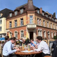 Menschen genießen das sonnige Wetter an einem Tisch vor dem historischen Gebäude 'Come Sempre' am Wettbachplatz in Sindelfingen., © Sindelfingen - Stuttgart-Marketing GmbH