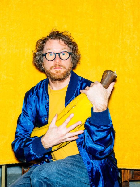 Ein Mann mit Brille und Bart in blauer Jacke h&auml;lt ein gro&szlig;es gelbes Objekt vor einem leuchtend gelben Hintergrund., &copy; Konzertkreis Triangel Compagnia Compostelli e.V.