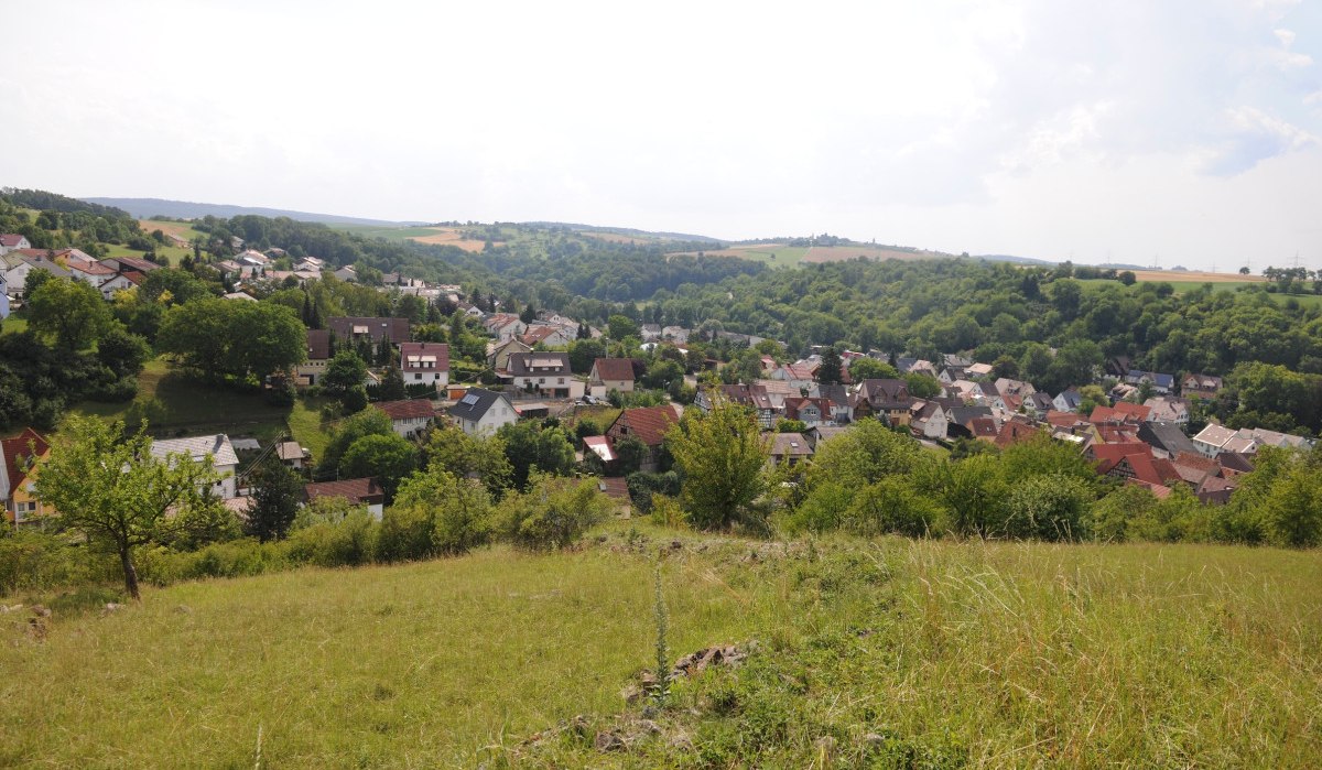Panoramablick auf ein Dorf mit vielen Häusern, umgeben von grüner Landschaft und Hügeln unter einem bewölkten Himmel., © Land der 1000 Hügel - Kraichgau-Stromberg