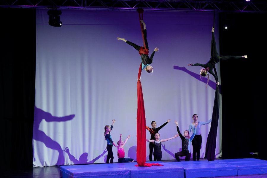 Kinder zeigen Luftakrobatik an roten und schwarzen Tüchern auf einer Bühne. Einige stehen auf Matten, während andere in der Luft hängen., © Kunstschule Labyrinth Kinder zeigen Luftakrobatik an roten und schwarzen Tüchern auf einer Bühne. Einige stehen auf Matten, während andere in der Luft hängen., © Kunstschule Labyrinth