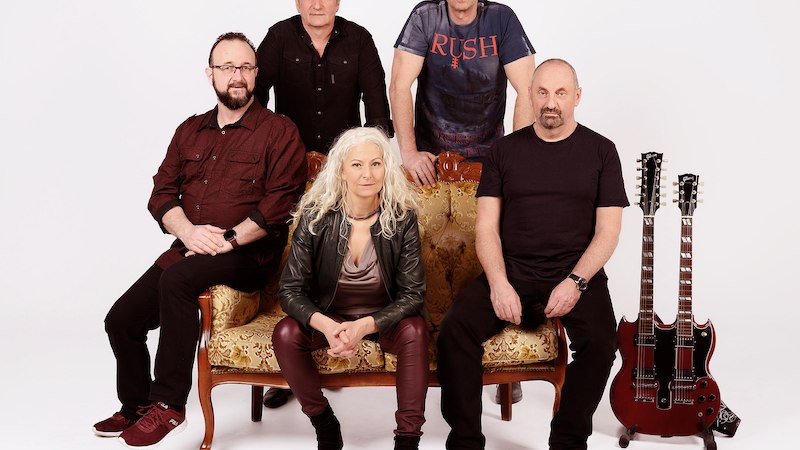 F&uuml;nf Personen sitzen und stehen um ein Sofa, zwei Gitarren stehen daneben. Eine Person tr&auml;gt ein T-Shirt mit der Aufschrift 'RUSH'., &copy; Scala Kultur Live gGmbH