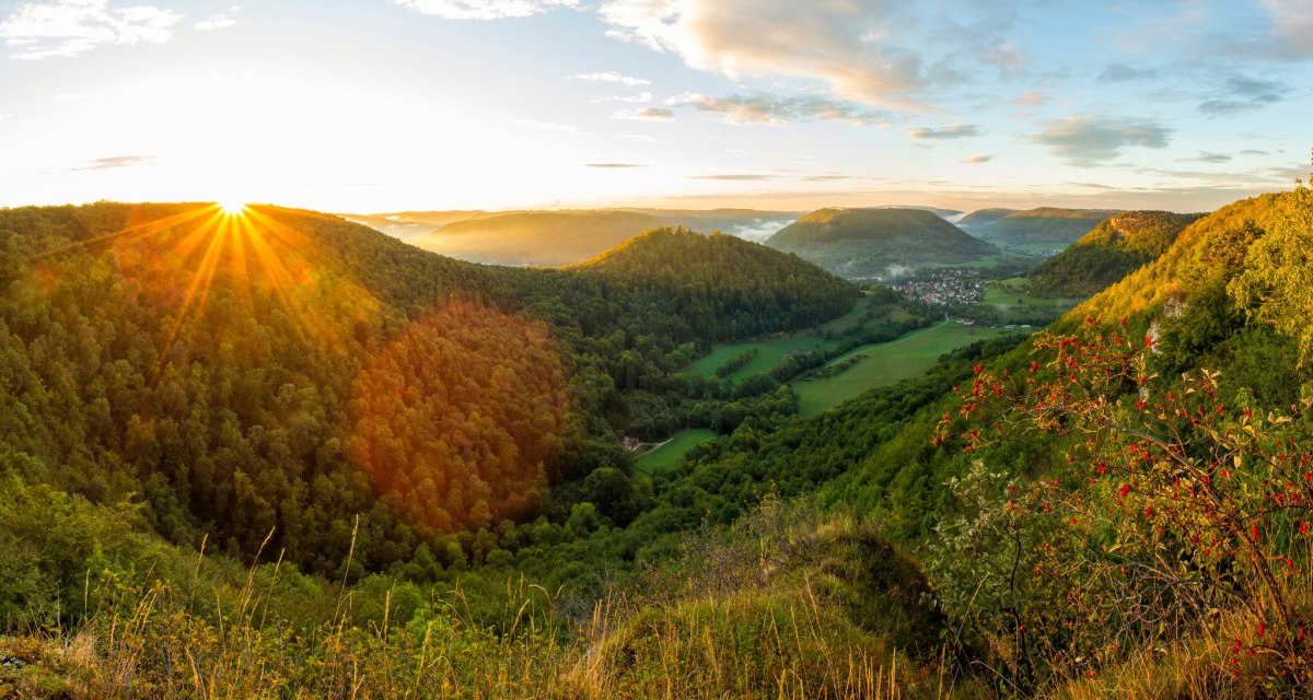 Sonnenaufgang &uuml;ber einer bewaldeten H&uuml;gellandschaft, gesehen vom Badfelsen. Die Sonne strahlt &uuml;ber die H&uuml;gel, w&auml;hrend Nebel in den T&auml;lern liegt., &copy; Landkreis G&ouml;ppingen
