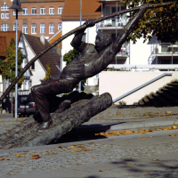 Bronzestatue eines Flößers, der mit einem langen Stab auf einem Baumstamm balanciert. Im Hintergrund Fachwerkhäuser und Herbstlaub auf dem Boden., © Stuttgart-Marketing GmbH Bronzestatue eines Flößers, der mit einem langen Stab auf einem Baumstamm balanciert. Im Hintergrund Fachwerkhäuser und Herbstlaub auf dem Boden., © Stuttgart-Marketing GmbH
