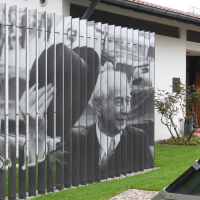 Das Theodor-Heuss-Haus in Stuttgart zeigt eine Fotoinstallation mit schwarz-weißen Bildern auf vertikalen Streben. Im Vordergrund sind Pflanzen zu sehen., © Stiftung Bundespräsident Theodor-Heuss-Haus / Franziska Kraufmann