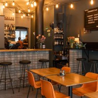 Gem&uuml;tliche Bar mit Holztischen, Barhockern und einer Theke. Lichterketten und ein Men&uuml;brett schm&uuml;cken die Wand., &copy; SMG, Sarah Schmid