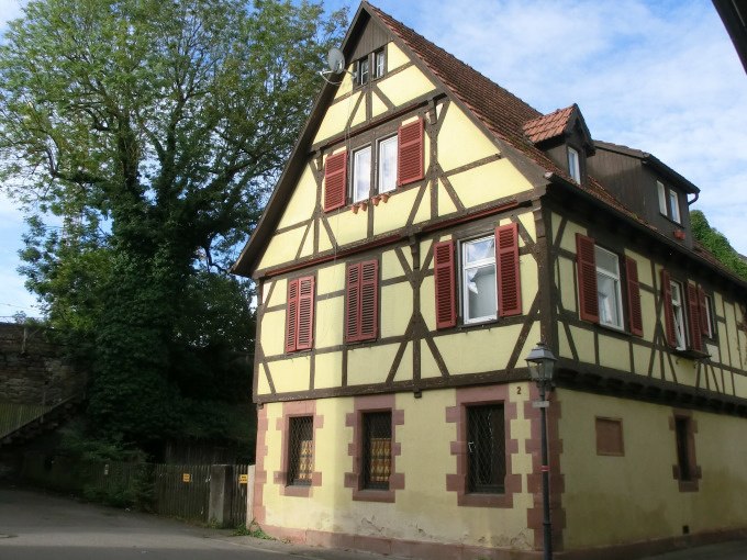 Ein traditionelles Fachwerkhaus mit gelber Fassade und roten Fensterl&auml;den, umgeben von B&auml;umen und blauem Himmel., &copy; Stadtverwaltung Weil der Stadt