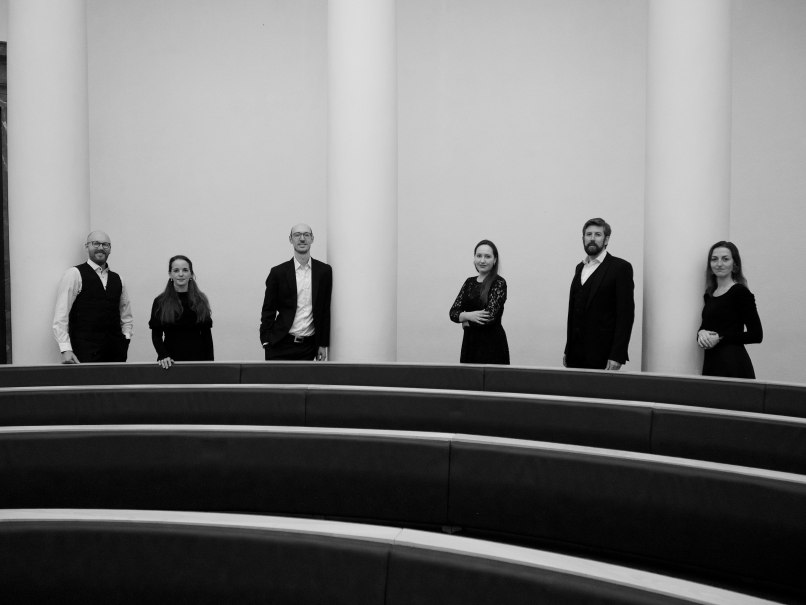 schwarz-wei&szlig; Bild der drei S&auml;ngerinnen und drei S&auml;nger von KlangKunst, zwischen den S&auml;ulen hinter den Bankreihen im Mausoleum stehend, &copy; Ensemble KlangKunst