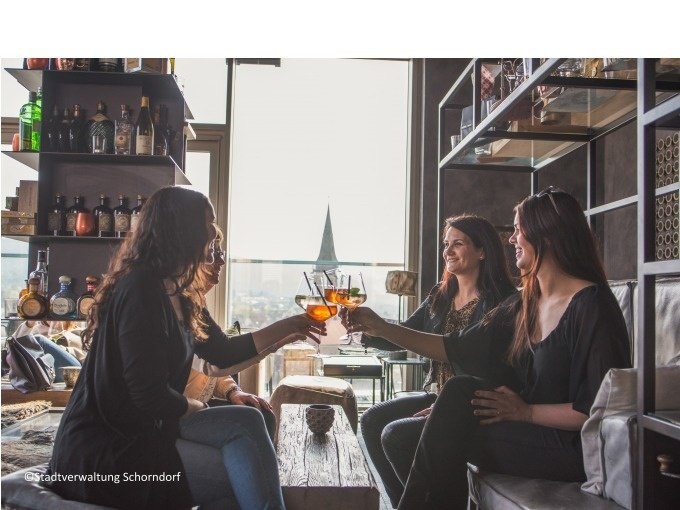 Vier Frauen sitzen in einer modernen Bar und stoßen mit Getränken an. Im Hintergrund sind Regale mit Flaschen zu sehen., © Eigenbetrieb Tourismus und Citymanagement Schorndorf Vier Frauen sitzen in einer modernen Bar und stoßen mit Getränken an. Im Hintergrund sind Regale mit Flaschen zu sehen., © Eigenbetrieb Tourismus und Citymanagement Schorndorf