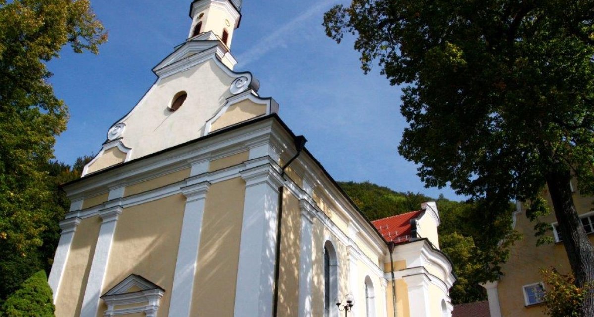 Die Wallfahrtskirche Ave Maria in Deggingen mit gelber Fassade und weißen Säulen, umgeben von Bäumen unter blauem Himmel., © Landkreis Göppingen Die Wallfahrtskirche Ave Maria in Deggingen mit gelber Fassade und weißen Säulen, umgeben von Bäumen unter blauem Himmel., © Landkreis Göppingen