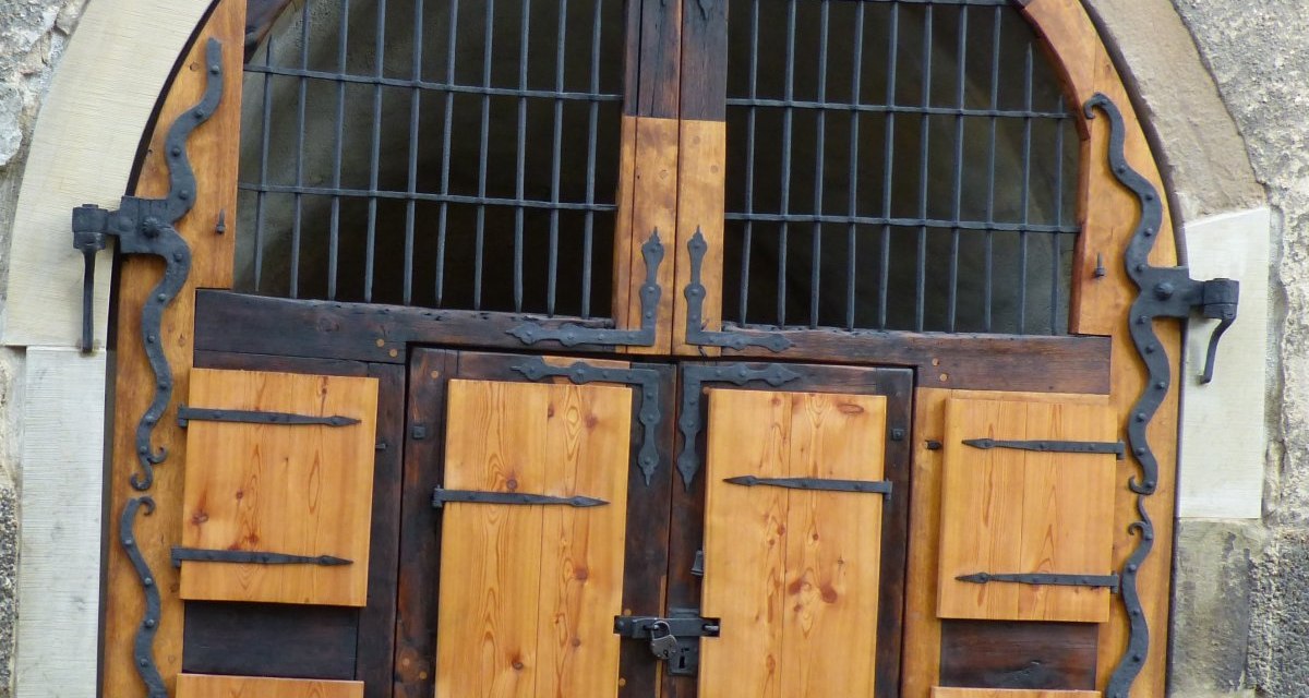 Ein rustikales Holztor mit dekorativen Metallbeschlägen in einem steinernen Gebäude. Das Tor hat ein Gitterfenster im oberen Bereich., © Land der 1000 Hügel - Kraichgau-Stromberg Ein rustikales Holztor mit dekorativen Metallbeschlägen in einem steinernen Gebäude. Das Tor hat ein Gitterfenster im oberen Bereich., © Land der 1000 Hügel - Kraichgau-Stromberg