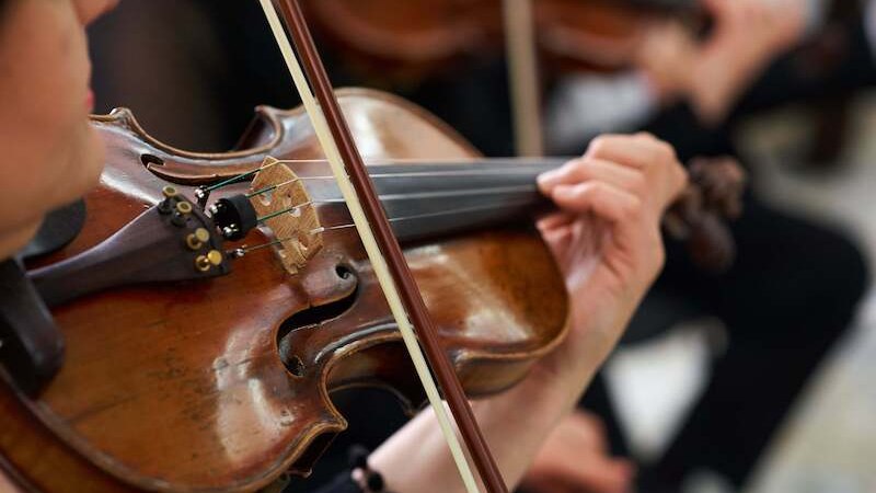 Eine Person spielt eine Geige in einem Orchester. Der Fokus liegt auf den H&auml;nden und dem Instrument., &copy; mbbl concerts