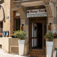 Eingang des Restaurants Huong Viet mit Blumenarrangements und einem E-Scooter auf dem Gehweg., © Stuttgart Marketing GmbH, Sarah Schmid