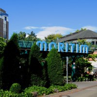 Au&szlig;enansicht des Maritim Hotels mit markantem Glasdach und umgeben von B&auml;umen und Pflanzen. Ein Weg f&uuml;hrt am Geb&auml;ude entlang., &copy; Maritim Hotelgesellschaft mbH