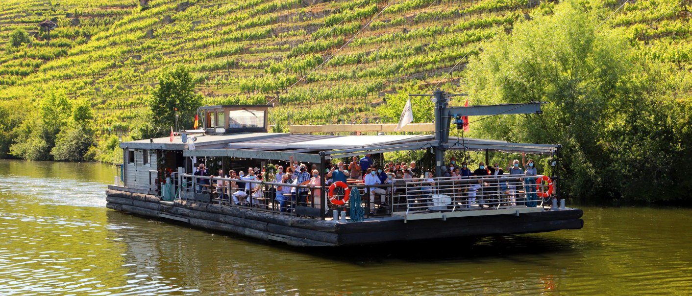 Ein Boot voller Menschen fährt auf einem Fluss entlang eines grünen Weinbergs bei sonnigem Wetter., © Stuttgart-Marketing GmbH Ein Boot voller Menschen fährt auf einem Fluss entlang eines grünen Weinbergs bei sonnigem Wetter., © Stuttgart-Marketing GmbH
