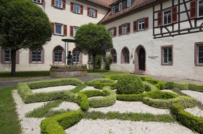 Ein gepflegter Garten mit kunstvollen Heckenmustern vor einem historischen Geb&auml;ude mit Fachwerk und roten Fensterl&auml;den., &copy; Stadtverwaltung Weil der Stadt