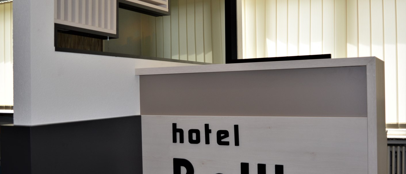 Moderner Rezeptionstresen im Hotel BaWu mit hellem Holz und stilvollem Design. Im Hintergrund sind vertikale Jalousien zu sehen., © Hotel BaWü