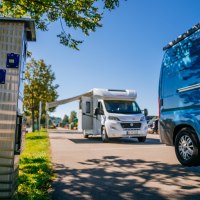 Wohnmobilstellplatz mit einem weißen Wohnmobil und einem blauen Van. Im Vordergrund eine Stromsäule, im Hintergrund Bäume und blauer Himmel., © Stuttgart-Marketing GmbH, Thomas Niedermüller Wohnmobilstellplatz mit einem weißen Wohnmobil und einem blauen Van. Im Vordergrund eine Stromsäule, im Hintergrund Bäume und blauer Himmel., © Stuttgart-Marketing GmbH, Thomas Niedermüller
