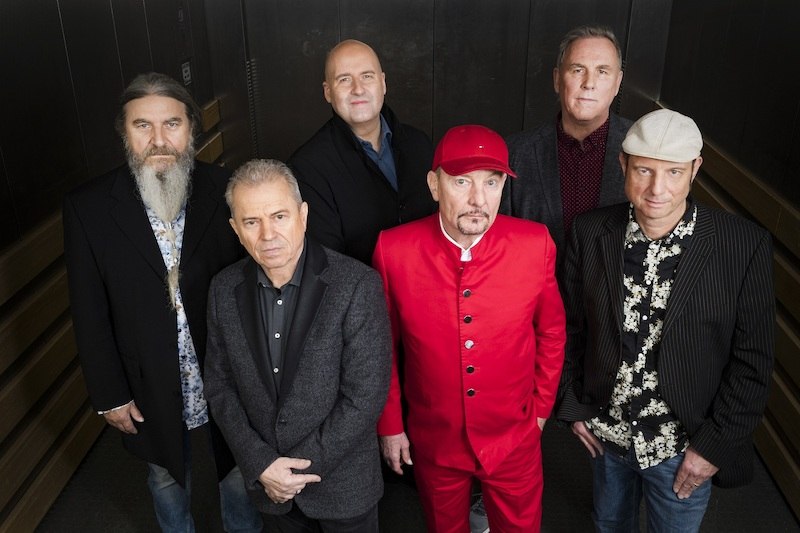 Sechs M&auml;nner stehen in einem Aufzug. Einer tr&auml;gt einen auff&auml;lligen roten Anzug und M&uuml;tze, die anderen sind in dunkler Kleidung., &copy; die Halle Kulturinitiative e.V.