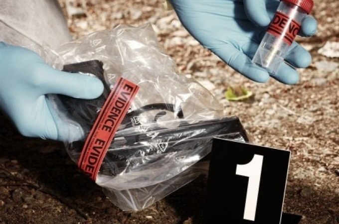 Ein Tatort mit Beweismaterial: Eine Waffe in einer Tüte und ein Beweisröhrchen, nummeriert mit 1, werden von einer Person mit Handschuhen untersucht., © Cool-Tours StattReisen Ein Tatort mit Beweismaterial: Eine Waffe in einer Tüte und ein Beweisröhrchen, nummeriert mit 1, werden von einer Person mit Handschuhen untersucht., © Cool-Tours StattReisen