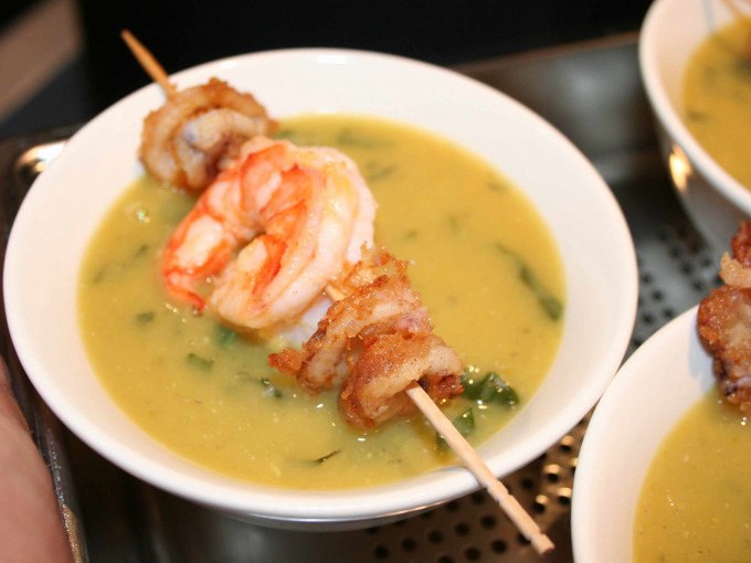 Eine Schüssel mit gelber Suppe, garniert mit einem Spieß aus Garnelen und gebratenem Fleisch., © Kultweine-Kochwelten-Kunstücke - Kochschule Sonja Lenz Eine Schüssel mit gelber Suppe, garniert mit einem Spieß aus Garnelen und gebratenem Fleisch., © Kultweine-Kochwelten-Kunstücke - Kochschule Sonja Lenz