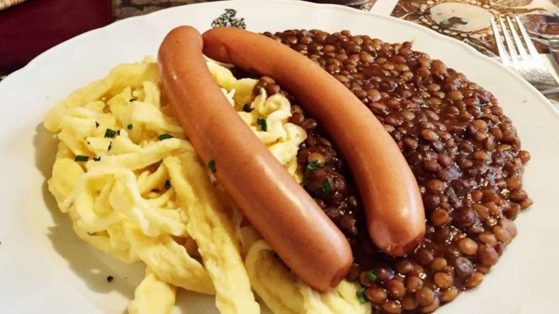 Ein Teller mit Linsen, Sp&auml;tzle und zwei W&uuml;rstchen, serviert auf einem Tisch mit Besteck., &copy; TMBW, Susi Maier