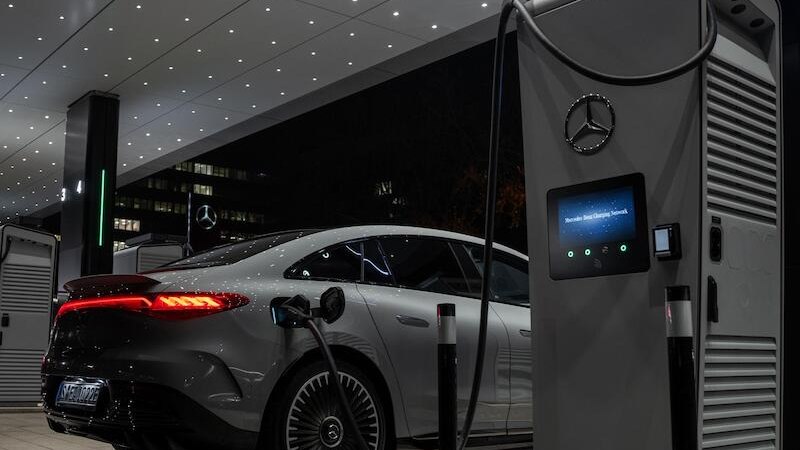 Ein Elektroauto wird nachts an einer modernen Ladestation aufgeladen. Die Umgebung ist beleuchtet und zeigt ein futuristisches Design., &copy; Mercedes-Benz AG