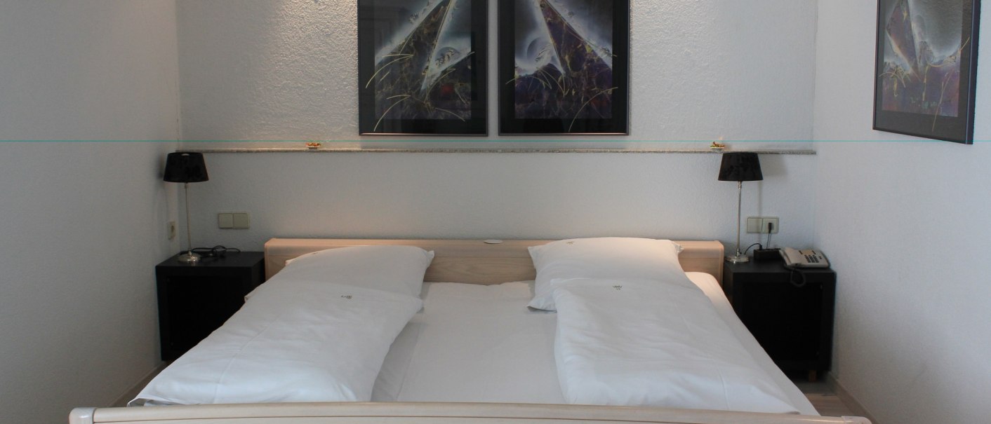 Ein Hotelzimmer mit einem Doppelbett, zwei Nachttischen mit Lampen und abstrakten Bildern an der Wand., © Hotel Spahr Ein Hotelzimmer mit einem Doppelbett, zwei Nachttischen mit Lampen und abstrakten Bildern an der Wand., © Hotel Spahr