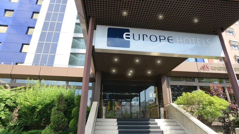 Eingang eines modernen Hotels mit dem Schild 'Europe Hotels Kongresshotel' &uuml;ber der Treppe. Links sind gr&uuml;ne B&uuml;sche zu sehen., &copy; Europe Hotels International