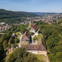 Luftaufnahme des Klosters Lorch, umgeben von Bäumen und einer kleinen Stadt im Hintergrund. Historische Gebäude und eine Kirche sind sichtbar., © Remstal Tourismus e.V.