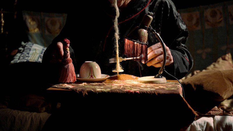 Eine Person in einem dunklen Raum mit einer Tischlampe, einer Tasse und einem dekorativen Quast auf einem Tisch., © Stadt Winnenden Eine Person in einem dunklen Raum mit einer Tischlampe, einer Tasse und einem dekorativen Quast auf einem Tisch., © Stadt Winnenden