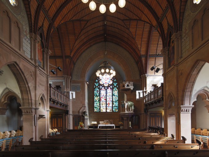 Kircheninnenraum mit Holzb&auml;nken, Buntglasfenster und gew&ouml;lbter Holzdecke. Ein Kronleuchter h&auml;ngt von der Decke., &copy; Stadtverwaltung Weil der Stadt