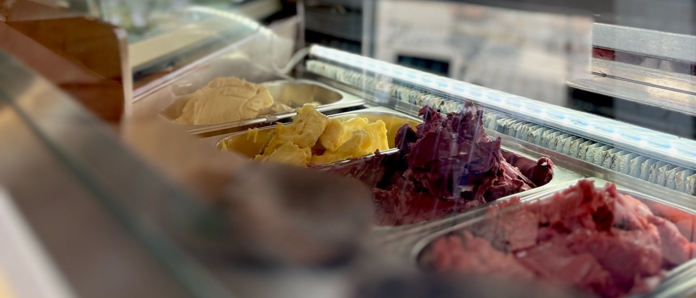 Innenansicht einer Eisdiele mit Eissorten in einer Vitrine. Im Hintergrund sind Tafeln mit Menüangeboten zu sehen., © E. Dogan Innenansicht einer Eisdiele mit Eissorten in einer Vitrine. Im Hintergrund sind Tafeln mit Menüangeboten zu sehen., © E. Dogan