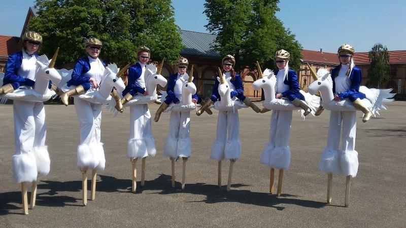 Kinder in Einhornkost&uuml;men stehen auf Stelzen in einer Reihe auf einem Platz. Sie tragen blaue Jacken und goldene Helme., &copy; Kunstschule Labyrinth