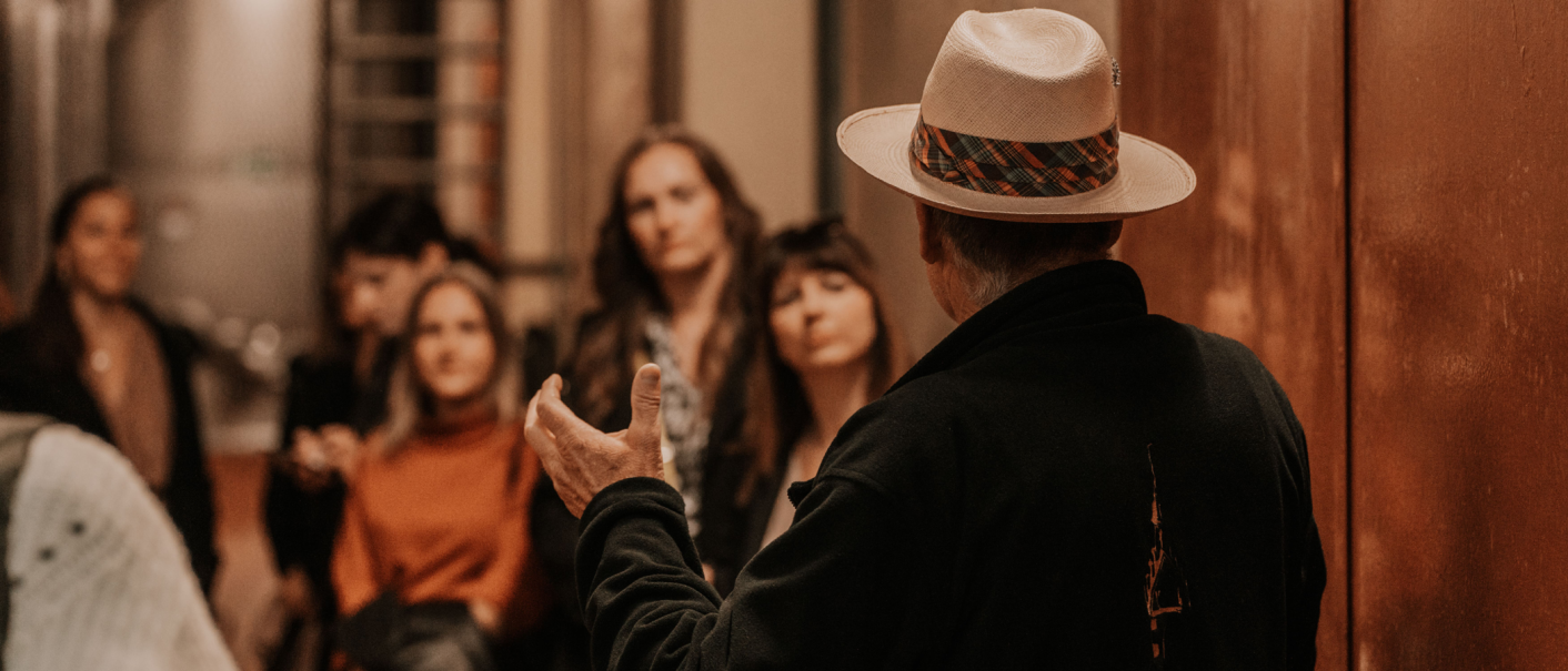 Ein Mann mit Hut erklärt einer Gruppe von Menschen etwas in einem Weinkeller. Die Zuhörer wirken interessiert., © Fellbacher Weingärtner eG Ein Mann mit Hut erklärt einer Gruppe von Menschen etwas in einem Weinkeller. Die Zuhörer wirken interessiert., © Fellbacher Weingärtner eG