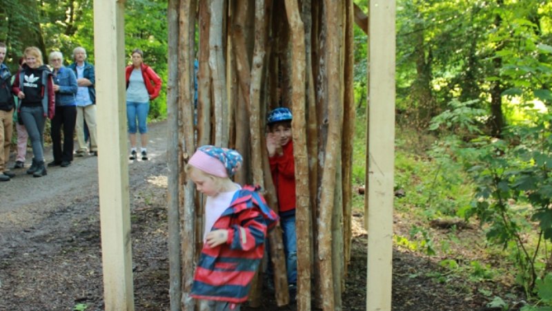 Kinder spielen in einer Holzkonstruktion aus Holzstämmen im Wald. Im Hintergrund stehen Erwachsene und beobachten die Szene., © Amt für Forsten Landkreis Böblingen Kinder spielen in einer Holzkonstruktion aus Holzstämmen im Wald. Im Hintergrund stehen Erwachsene und beobachten die Szene., © Amt für Forsten Landkreis Böblingen