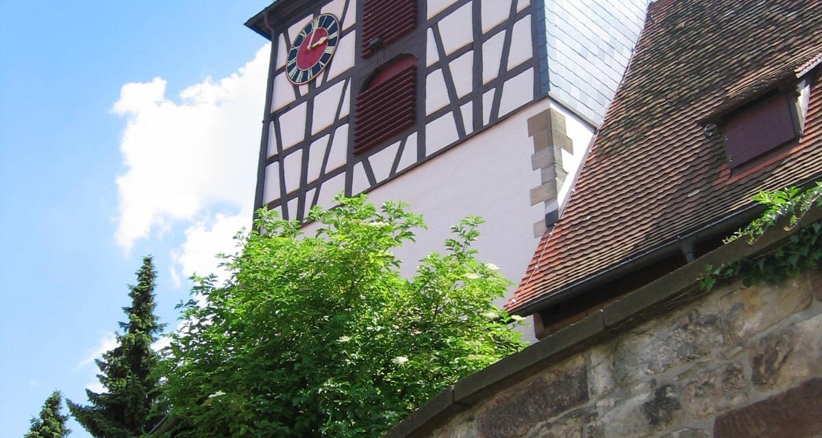 Fachwerkkirchturm der St. Veit Kirche in Ensingen mit Uhr und rotem Dach vor blauem Himmel., © Land der 1000 Hügel - Kraichgau-Stromberg Fachwerkkirchturm der St. Veit Kirche in Ensingen mit Uhr und rotem Dach vor blauem Himmel., © Land der 1000 Hügel - Kraichgau-Stromberg