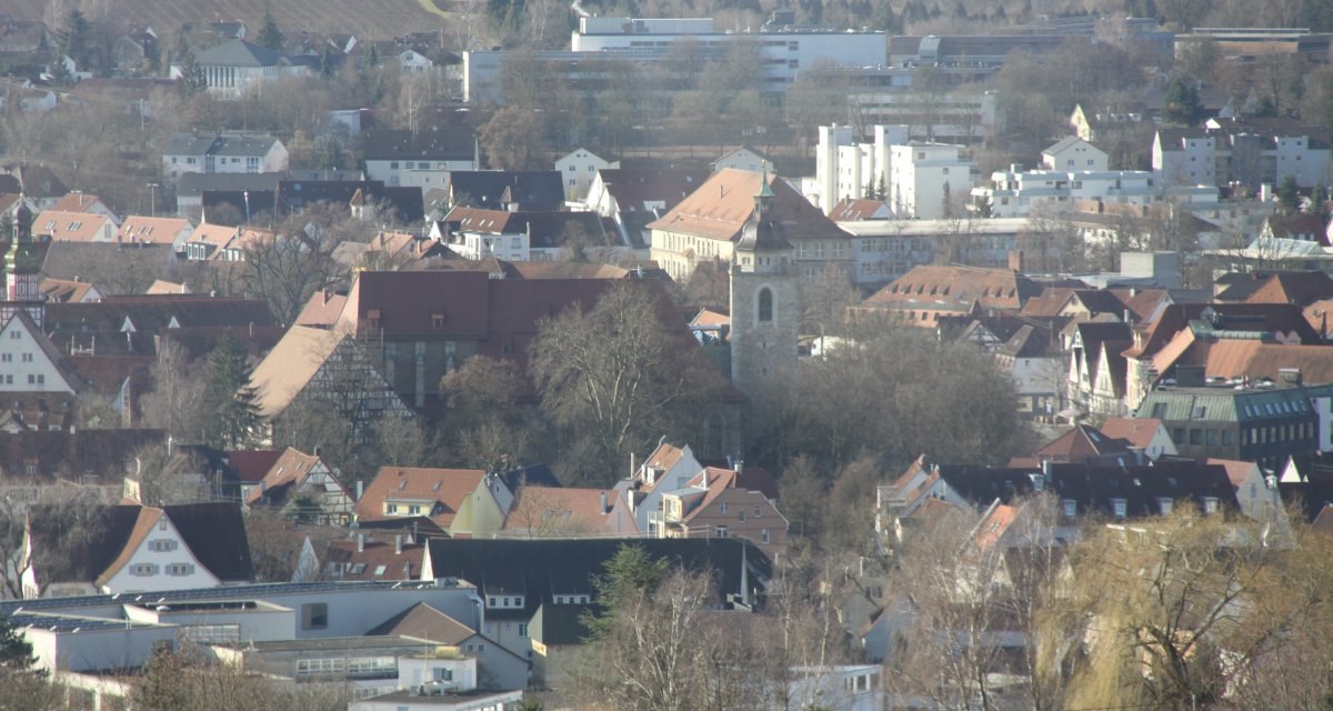 Blick auf eine Stadt mit vielen roten Dächern, einem markanten Kirchturm und umliegenden Gebäuden. Im Hintergrund sind Felder und Bäume zu sehen., © Schwäbische Alb Tourismusverband e.V. Blick auf eine Stadt mit vielen roten Dächern, einem markanten Kirchturm und umliegenden Gebäuden. Im Hintergrund sind Felder und Bäume zu sehen., © Schwäbische Alb Tourismusverband e.V.
