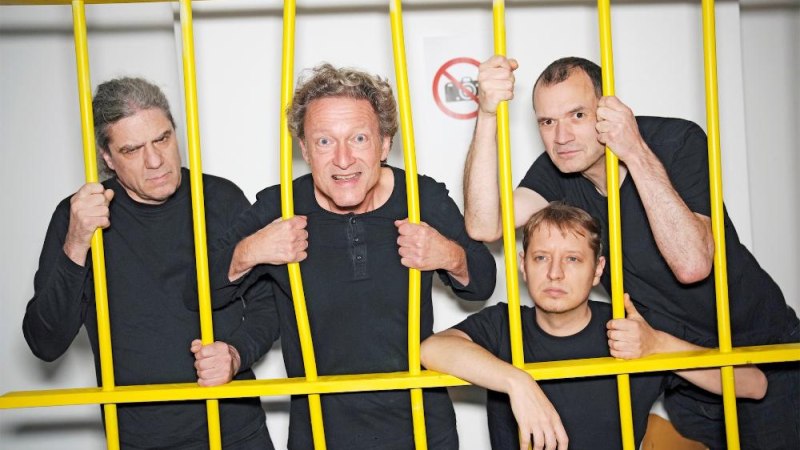 Vier M&auml;nner in schwarzen Hemden posieren hinter gelben Gitterst&auml;ben. Sie schauen ernst und konzentriert in die Kamera., &copy; Foto South Quartett