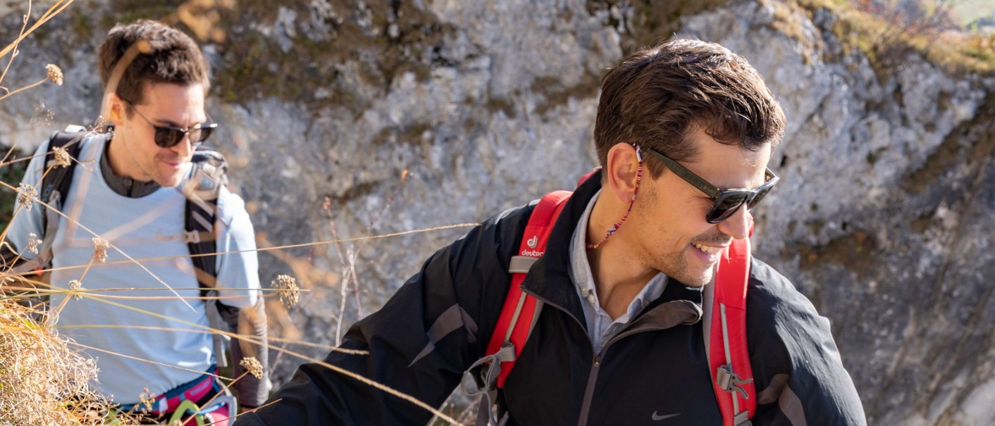 Zwei Personen klettern an einem steilen Hang. Eine Person trägt einen roten Rucksack. Ein Seil liegt auf dem Boden., © SMG, Martina Denker