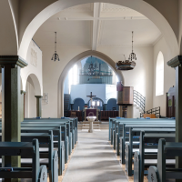 Innenansicht der Kirche mit blauen Bänken, Altar, Kanzel und Orgel im Hintergrund. Helle Wände und große Bögen prägen den Raum., © Stadt Gaildorf