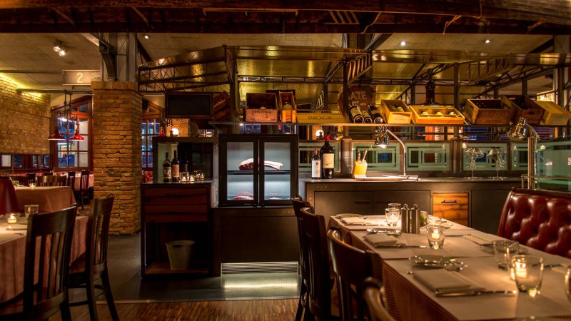 Stilvolles Restaurant mit Backsteinwänden, gedeckten Tischen und Weinflaschen. Warmes Licht schafft eine gemütliche Atmosphäre., © ©Pier 51 Stilvolles Restaurant mit Backsteinwänden, gedeckten Tischen und Weinflaschen. Warmes Licht schafft eine gemütliche Atmosphäre., © ©Pier 51