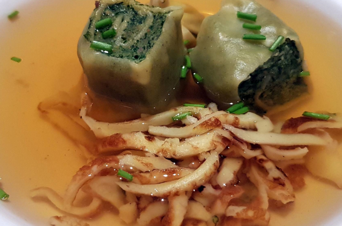 Zwei Maultaschen in klarer Brühe, garniert mit Schnittlauch und Pfannkuchenstreifen, serviert in einer weißen Schüssel., © Kultweine-Kochwelten-Kunstücke - Kochschule Sonja Lenz