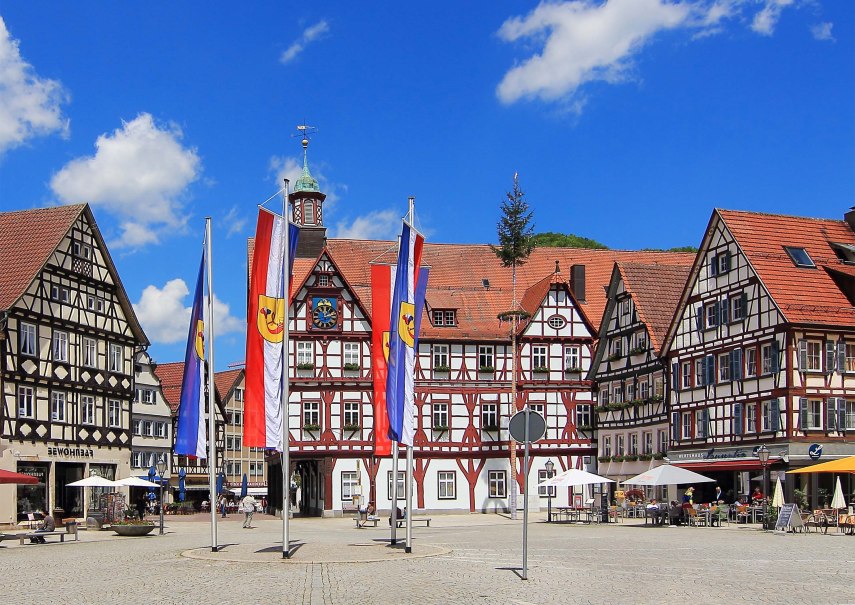 Historischer Marktplatz mit Fachwerkhäusern, Fahnen und blauem Himmel in einer deutschen Stadt.