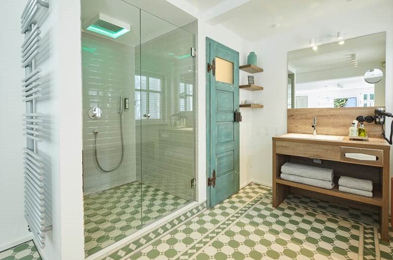 Modernes Badezimmer mit Glasdusche, grünem Fliesenboden, Holzwaschtisch und türkisfarbener Tür. Handtücher und Pflegeprodukte sind bereitgestellt., © Hotel Restaurant Bachofer Modernes Badezimmer mit Glasdusche, grünem Fliesenboden, Holzwaschtisch und türkisfarbener Tür. Handtücher und Pflegeprodukte sind bereitgestellt., © Hotel Restaurant Bachofer