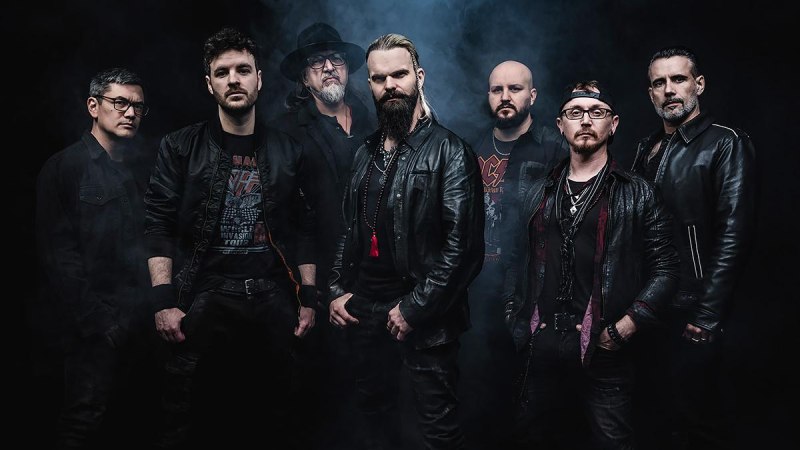 Sieben Männer in schwarzer Kleidung posieren vor einem dunklen, nebligen Hintergrund. Sie tragen Lederjacken und haben ernste Gesichtsausdrücke., © Music Circus Concertbüro GmbH & Co. KG