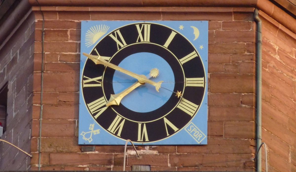 Große Uhr mit römischen Ziffern auf blauem Hintergrund an einem Backsteingebäude. Verzierungen mit Sonne, Mond und Sternen., © Natur.Nah. Schönbuch & Heckengäu Große Uhr mit römischen Ziffern auf blauem Hintergrund an einem Backsteingebäude. Verzierungen mit Sonne, Mond und Sternen., © Natur.Nah. Schönbuch & Heckengäu