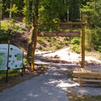 Eingangsportal zu den Sommerberg Aufstiegswegen mit Infotafel und Holzbank in einem Waldgebiet., © Nördlicher Schwarzwald