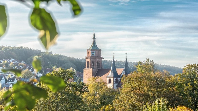 Die Peter und Paul Kirche in Weil der Stadt erhebt sich majest&auml;tisch &uuml;ber die herbstliche Landschaft, umgeben von buntem Laub und klarem Himmel., &copy; &copy; Stuttgart-Marketing GmbH, Martina Denker