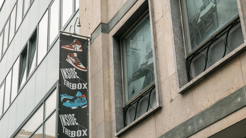 Fassade eines Gebäudes mit einem Schild 'Inside The Box' und einem gezeichneten Café im Fenster., © SMG, Sarah Schmid